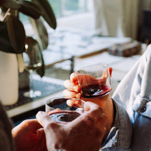 Load image into Gallery viewer, Two people holding glasses of red wine in a cozy indoor setting.