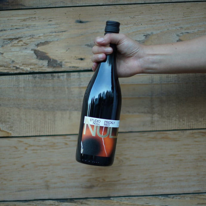 Hand holding a bottle against a wooden background